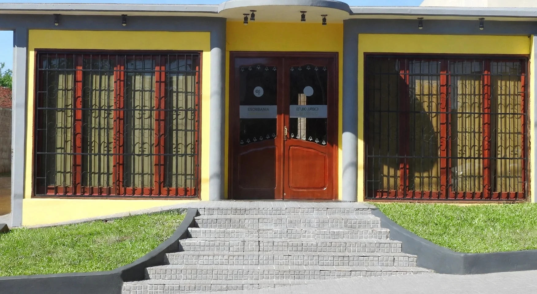 Frente de la Escribanía Ferreira en Av. Bustamante 3175, Posadas: puerta de acceso con los carteles de escribanía y estudio jurídico